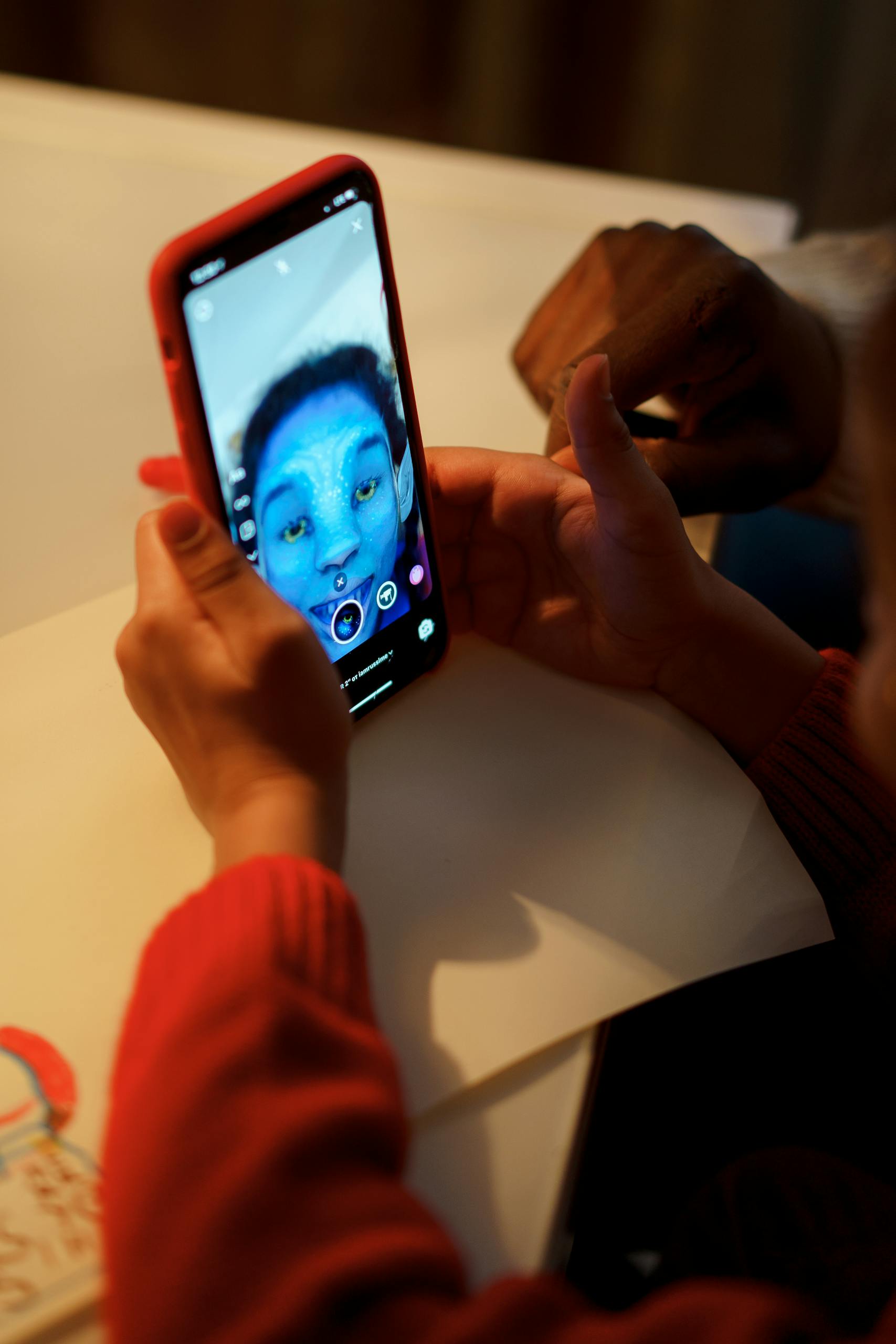 A child uses a smartphone with a fun facial filter, indoors, showcasing modern technology and creativity.